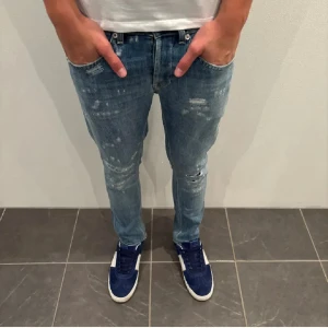 Blå Dondup jeans med slitningar - Snygga blå jeansbyxor från Dondup med slitningar och en slim passform. De har en klassisk femficksdesign och är perfekta för en avslappnad stil (modell George). Sköna jeans för sig som är s”hiit grääh. (För små för mig så lånade bilder av han jag köpte av)