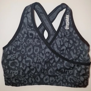 Leopardmönstrad sportbh från Gymshark - Bh:n har korsade band i ryggen och en omlott-design framtill. Perfekt för träning med sin bekväma passform och stilrena look. Knappt använd. Säljer matchande tights. 