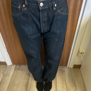 Levis 501 jeans - Klassiska Levis 501 jeans i mörkblå denim med knappgylf. De har en rak passform och är högmidjade. Perfekta för en avslappnad look. 