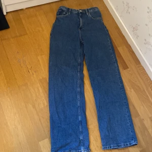 Blå jeansbyxor - Snygga blå jeansbyxor med hög midja och en avslappnad, wide passform. Perfekta för en casual look. Klassisk design med fem fickor och knappgylf.