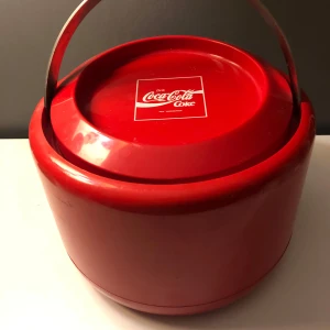 Röd Coca-Cola ishink från Stelton - Säljer en cool röd Coca-Cola ishink designad av Erik Magnussen för Stelton. Tillverkad i Danmark, denna hink har en retro stil med ett praktiskt handtag för enkel transport. Perfekt för att hålla drycker kalla på festen! 🥤