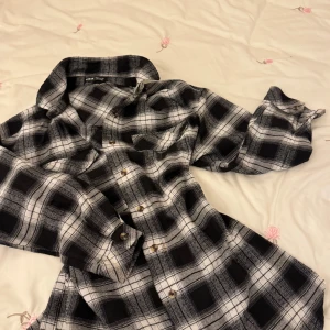 Svartvit rutig skjorta från Shein - Snygg svartvit rutig skjorta från Shein med klassisk krage och knappar framtill. Perfekt för en avslappnad stil. Skjortan har långa ärmar och ett tidlöst rutmönster.