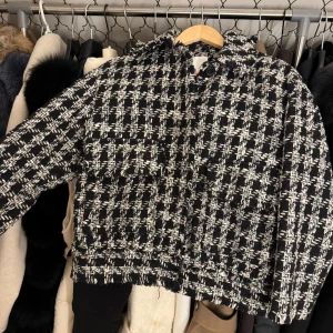 Svartvit rutig jacka - Snygg svartvit rutig jacka med en klassisk look. Jackan har en lös passform och långa ärmar, perfekt för höst och vår. Den är tillverkad i ett mjukt material som ger en bekväm känsla. Perfekt för att ge din outfit en stilfull touch.