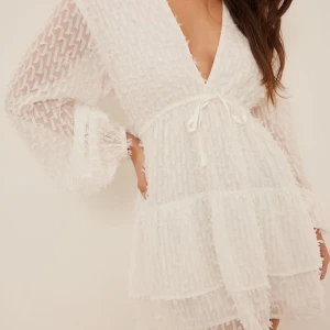 Vit klänning med volanger - Säljer en söt vit klänning med volanger och v-ringning. Klänningen har långa ärmar och ett knytband i midjan för en fin passform. Perfekt för sommarens alla tillfällen! Passar st s jag säljer pga för stor har st 32 som referens 