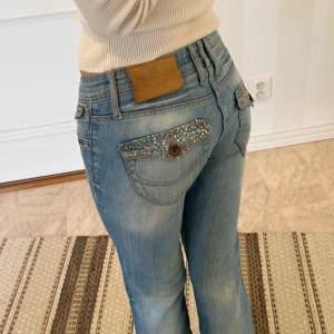 Blå jeans med strassdetaljer - Blå jeans med strassdetaljer på fickorna. 