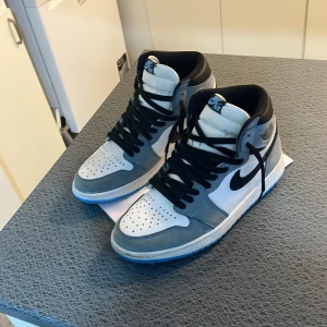 Nike Air sneakers i blå och vit   - Snygga Nike Air sneakers i en stilren kombination av grått och vitt med svarta detaljer. Skorna har en klassisk snörning och en bekväm passform. Perfekta för en sportig look.