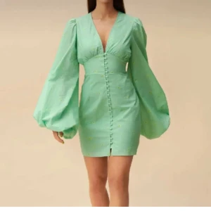 Mintgrön klänning med puffärmar - Snygg grön klänning från adoore med djup v-ringning och puffiga långa ärmar. Klänningen har knappar framtill och en figurnära passform som framhäver midjan. Perfekt till studentmottagning!💚