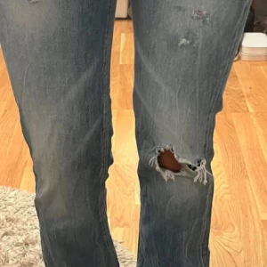Blå jeans från Hilfiger - Snygga blå jeans från Hilfiger med slitna detaljer och en klassisk femficksdesign. De har en låg midja. Storlek 36, säljer då dom va för stora. Lånade bilder 