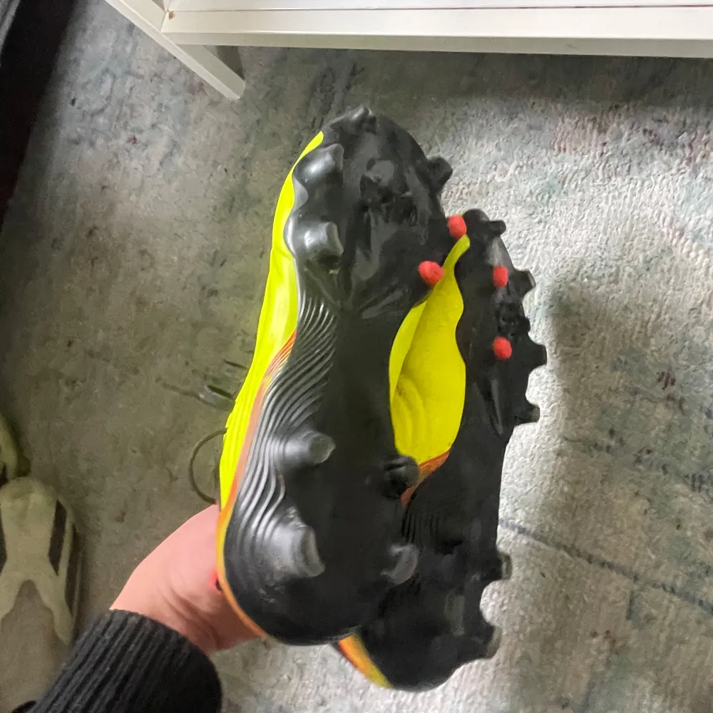 Snygga gula fotbollsskor från Adidas med svarta och röda detaljer. Perfekta för fotbollsspelare som vill sticka ut.. Kengät.