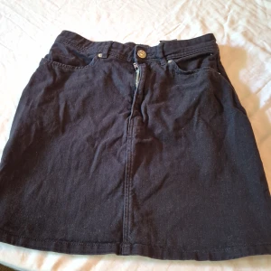 Svart jeanskjol från Divided - Säljer en snygg svart jeanskjol från Divided i storlek 34 (S). Kjolen har en klassisk design med dragkedja och knapp framtill. Perfekt för både vardag och fest! 🖤