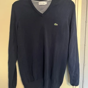Mörkblå tröja från Lacoste - Säljer en snygg mörkblå tröja från Lacoste i storlek S. Tröjan är i bra skick och har en klassisk v-ringning. Perfekt för höst och vinter! pris kan diskuteras. 