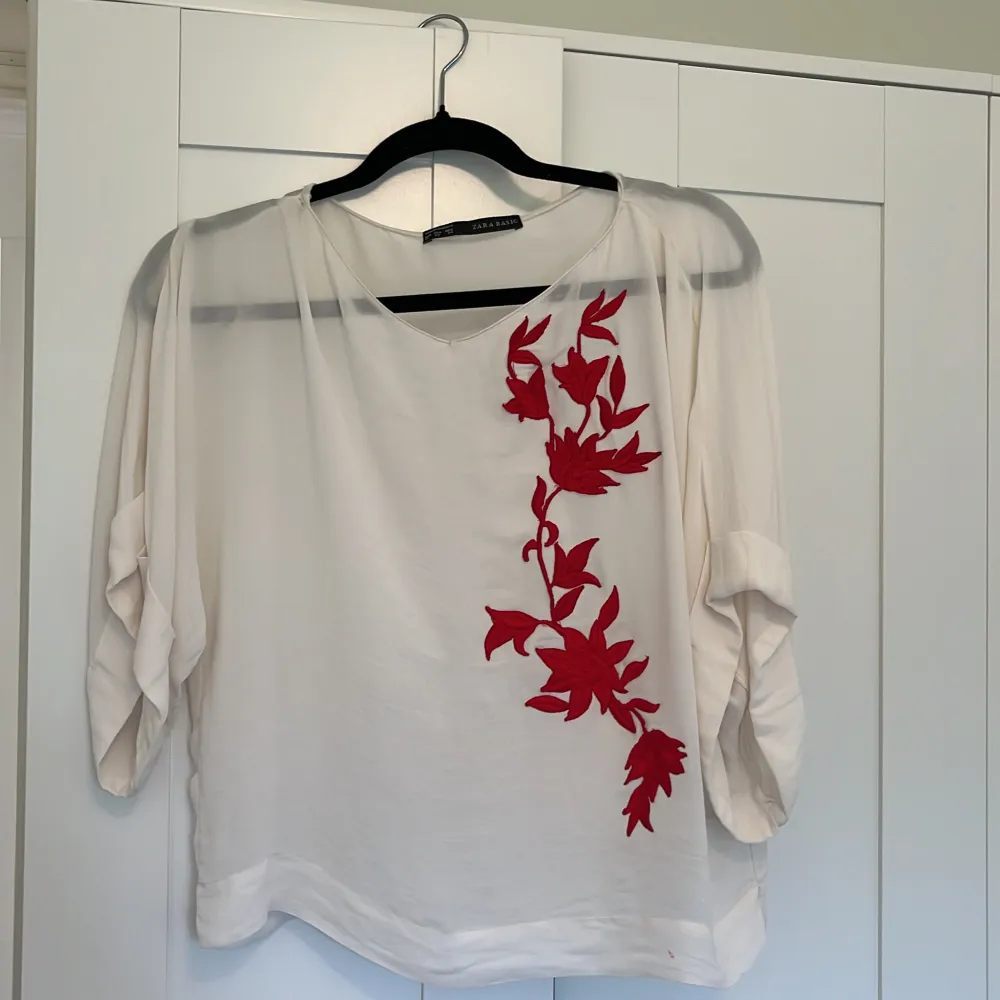 Blus i ivory färg med rött blommigt mönster . Blusar.