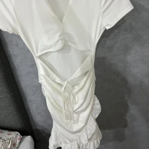 En kort vit klänning  - Klänningen är öppen från magen och den är utsvängd vid midjan ner. Skicket på den är bra inga skador, ingen fläck. 