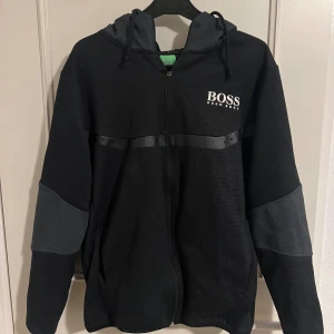 Hugo Boss Zip Tröja - Hugo Boss Zip tröja i begagnat skick (Replika) Färg: Svart/Grå Storlek: Står L men sitter som S