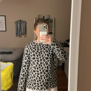 Grå leopardmönstrad tröja från 365 Three Sixty Five - Säljer en snygg grå tröja med leopardmönster från 365 Three Sixty Five. Tröjan har långa ärmar och en rund halsringning. Perfekt för att ge din outfit en trendig touch 🐆