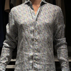 Stenströms Blommig skjorta. M - Snygg blommig skjorta med långa ärmar och knappar framtill. Skjortan har ett färgglatt mönster i blått, grönt och gult på en vit bakgrund. Perfekt för att liva upp garderoben! Linne