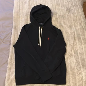 Svart Polo Ralph Lauren hoodie - Säljer en riktigt najs svart hoodie från Polo Ralph Lauren i nästan nyskick. Använd ett fåtal gånger. Nypris 2195. Mitt pris 899.