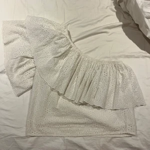 Vit offshoulder blus från YAS - Säljer en söt vit offshoulder blus från YAS med broderade detaljer. Blusen har en volang som ger en romantisk känsla och är perfekt för varmare dagar. Den är tillverkad i ett lätt och luftigt material.