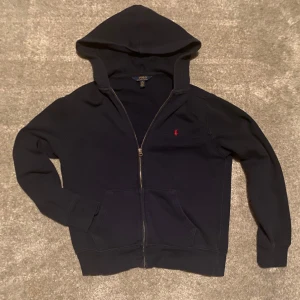 Mörkblå hoodie från Polo Ralph Lauren - Säljer en stilren mörkblå hoodie från Polo Ralph Lauren med dragkedja och huva⭐️| Passar dig mellan 147-155cm | skick 8/10 | pris går att diskutera🤝