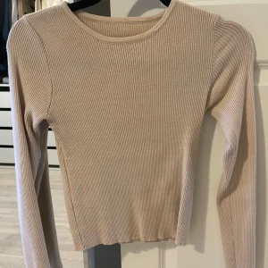 Beige ribbad tröja - Säljer en stilren beige ribbad tröja med långa ärmar. Perfekt för en avslappnad och trendig look. Passar bra till både jeans och kjol.