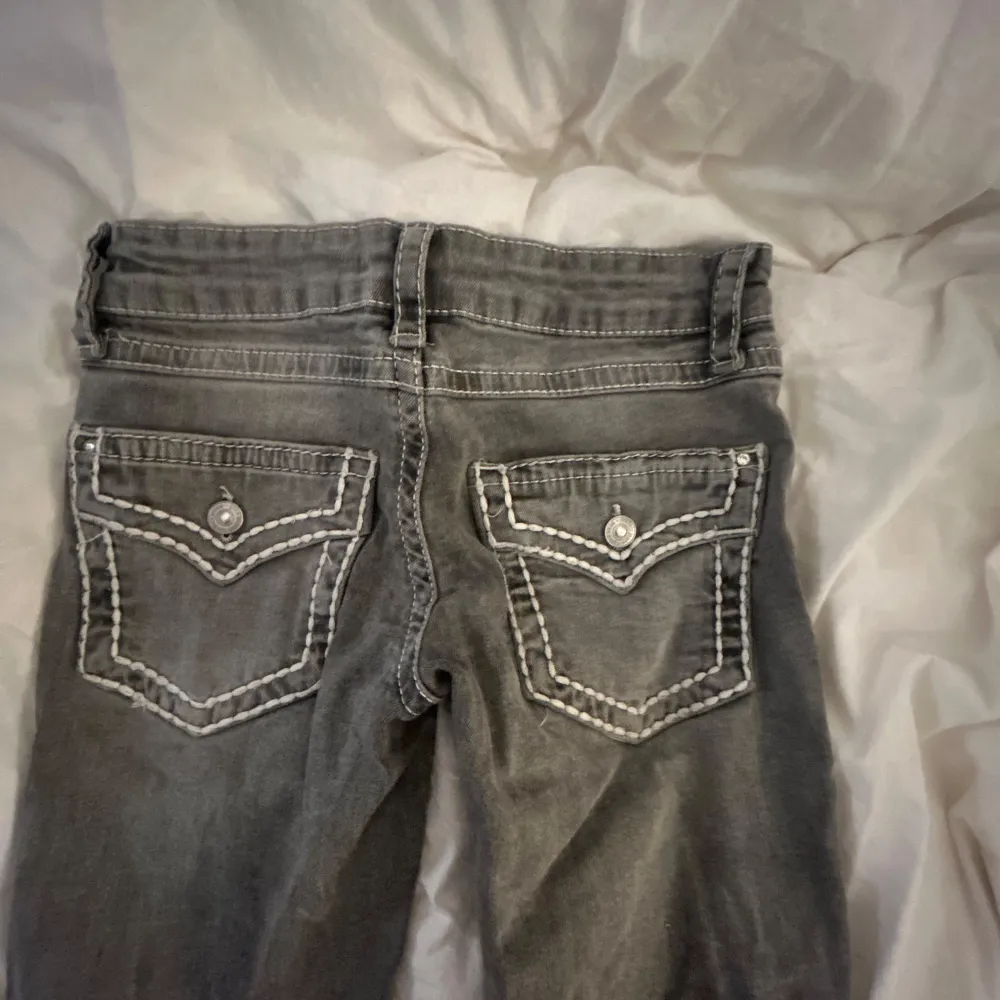 Snygga grå jeans med vita dekorativa sömmar på bakfickorna. De har en klassisk femficksdesign och en knappgylf. Perfekta för en avslappnad stil. Efterlikanar miss me jeans.. Farkut & Housut.