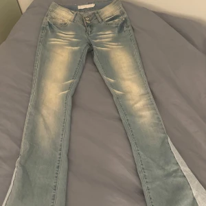 Blå jeans med slits från Big Mantis - Snygga blå jeans från Big Mantis med en unik slitsdetalj längs benen. De har en klassisk femficksdesign och dubbla knappar i midjan. Fint skick!! Jätte coola detaljer, innebenslängden 82cm! Tvärs över midjan 38 