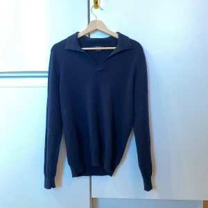 Massimo Dutti Ull/Kaschmir Polotröja - Säljer en elegant mörkblå tröja från Massimo Dutti i ull och kashmir. Tröjan har en klassisk krage och långa ärmar, perfekt för kyligare dagar. Den är tillverkad i Kina och ger en lyxig känsla med sitt mjuka material.