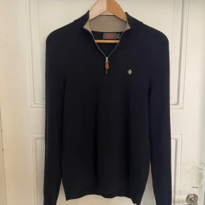 Mörkblå tröja med dragkedja från Morris - Säljer en stilren mörkblå tröja från Morris med dragkedja och en liten broderad detalj på bröstet. Tröjan är gjord av 100 % Merino Ull och är i fint skick:)