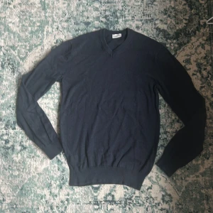 Mörkblå v-neck tröja från John Henric - Säljer en stilren mörkblå tröja från John Henric. Tröjan har en v-ringad design och är tillverkad i ett mjukt material. Utmärkt skick. Storlek Small