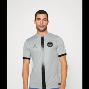 Grå fotbollströja från Jordan x PSG - Snygg grå fotbollströja säljer pga att den inte andvänds. Den har text på armarna där de står goat men de har gått bort så de är samma tröja fast det står qatar något i mitten av tröjan. Står neymar jr på baksidan och nummer 10 