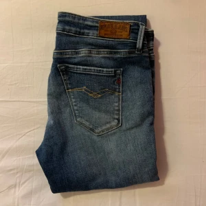 Replay jeans luz W29 L32 - Snygga blå jeans från Replay med klassisk femficksdesign och knappgylf. Perfekta för en avslappnad stil. Märkeslappen på baksidan ger en extra touch av stil. Bra skick men med liten slitning på knäet.