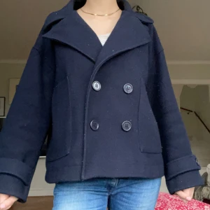 Mörkblå skepparkavaj - Snygg mörkblå skepparkavaj med dubbelknäppning och bred krage. Jackan har långa ärmar och två stora fickor framtill. Perfekt för en stilren look. Lite nopprig på vissa ställen men inget som syns mycket💕💕Strl XS/S