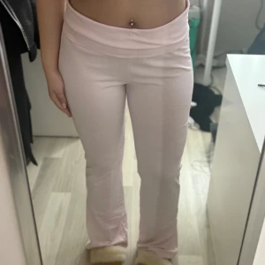Rosa mjukisbyxor - Säljer ett par bekväma rosa mjukisbyxor med bootcut-stil. De är lågmidjade och perfekta för en avslappnad look. Byxorna har en bred linning som ger extra komfort.
