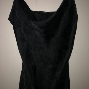 Söt liten svart klänning - Älskar denna klänning! Men kommer inte använda den längre. Därför säljer jag denna eleganta klänningen från BikBok med ett sött blommönster. Klänningen har smala axelband och en v-ringad design som ger en stilren look.  Söt sned volang på kjolen. Perfekt för en kväll ute eller en speciell tillställning. Nytt skick! Har används en gång.