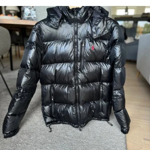 Ralph Lauren Glossed Down XL  - Snygg svart pufferjacka från Ralph Lauren med huva och dragkedja. Använd men i väldigt bra skick!