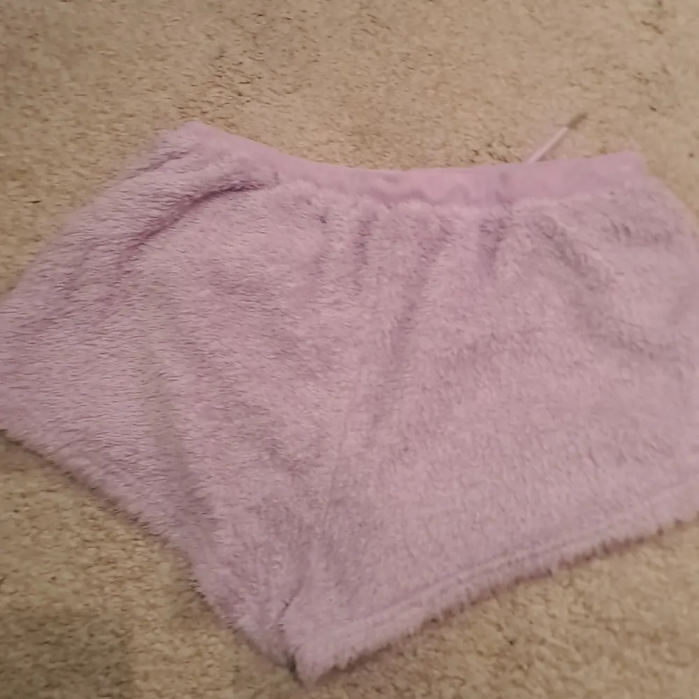 Mysiga lila shorts i fluffigt material med snörning i midjan. Perfekta för en avslappnad dag hemma eller som ett bekvämt lager under kyligare dagar.. Shortsit.
