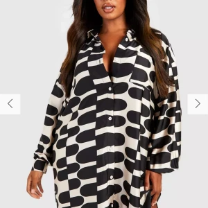 Oversize mönstrad skjortklänning från Boohoo - Snygg och trendig skjortklänning från Boohoo i svartvitt mönster. Klänningen har en lös passform med långa ärmar och knappar framtill. Storlek 46