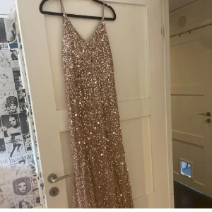 Glittrig långklänning med paljetter - Säljer en fantastisk glittrig långklänning i champagnefärg med paljetter. Klänningen har smala axelband och en elegant passform som passar perfekt för festliga tillfällen. 