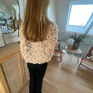 Rosa tröja med volangdetaljer - Säljer en unik rosa tröja med volangdetaljer över hela ytan. Tröjan har långa ärmar och en mjuk, bekväm passform. Perfekt för att ge en extra touch till din outfit. Passar bra till både jeans och kjol.