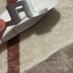 Vitt bälte med metallspänne - Snyggt vitt bälte med ett stilrent metallspänne. Perfekt för att ge en modern touch till din outfit. Bältet har en slät yta och är lätt att matcha med olika stilar.