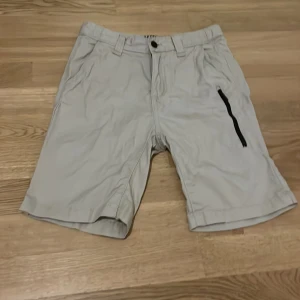 Beige shorts från Warp - Säljer ett par beige shorts från Warp. De har en dragkedja och knapp framtill samt en praktisk ficka med dragkedja på sidan. Perfekta för en avslappnad stil.