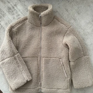 Beige teddyjacka med dragkedja - Supertrendig mysig beige teddyjacka med hög krage och dragkedja framtill. Jackan har långa ärmar och två stora fickor. Perfekt för kyliga dagar. Säljer då jag vill köpa en annan💗