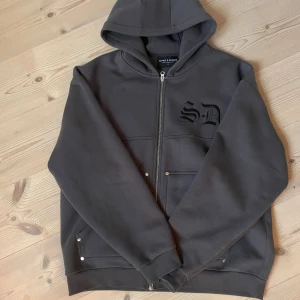 Grå hoodie från Supply & Demand - Säljer en stilren grå hoodie från Supply & Demand med dragkedja och broderad logga på bröstet. Tröjan har en klassisk design med huva och praktiska fickor framtill. Perfekt för en avslappnad stil. Nästan helt oanvänd säljer för råka bästella fel storlek köpt för 650 säljer för 450 kan pris kan diskuteras 