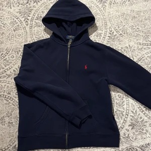 Ralph Lauren Zip Up - Säljer min blåa Polo Ralph Lauren zipup eftersom den börjar bli för liten. Den är i 7/10 skick. Nypris runt 1.200kr Storlek 14-16/160cm   Inga skador förutom en liten bit tråd som syns i fjärde bilden.
