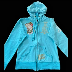 Turkos hoodie från Christian Audigier - Säljer en snygg turkos hoodie från Christian Audigier. Den har en dragkedja framtill och en cool design både på ryggen och bröstet! Bra skick! 💞