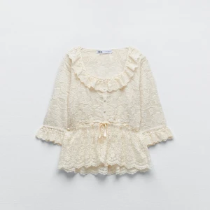 Beige spetsblus från Zara - Superfin beige spetsblus från Zara med volangdetaljer och trekvartsärm. Den har en söt knytning i midjan och är perfekt för en romantisk look. Passar både till vardags och fest! Privat för fler bilder💕