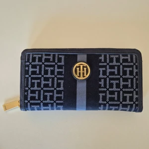 Plånbok Tommy Hilfiger - Plånbok från märket Tommy Hilfiger. Använd några gånger. Rymlig och stechbar, mycket får plats. Mjuk material. Många fickor för kort mm.  20,5 cm lång och 10 cm hög