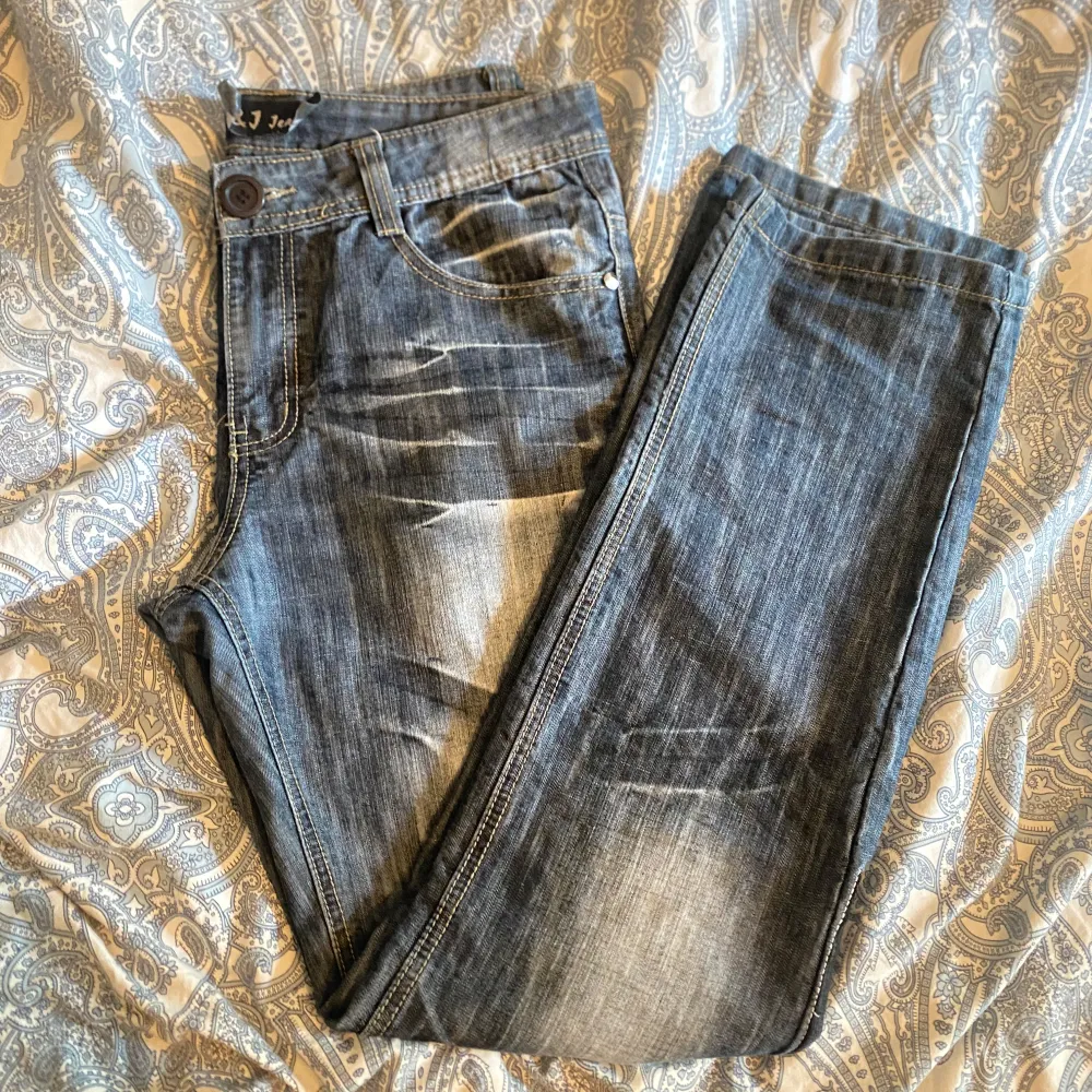 Säljer ett par asballa jeans från J&J Jeans. De är straight leg, blåa med ett unikt broderi av vingar och mönster på baksidan. Inga defekter, knappen är inte originell utan påsydd. Skulle nog säga att midjemåttet är emellan 40-42, OBS ej stretchiga. . Jeans & Byxor.