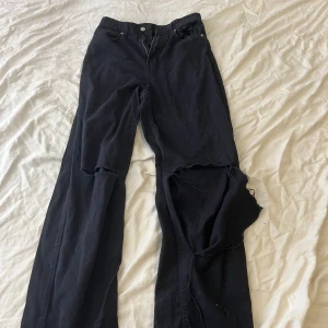 Svarta jeans  - Ett par svarta jeans med hål i.