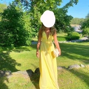 Gul långklänning med öppen rygg - Säljer mina superfina gula balklänning! Klänningen har en v-ringad design, elegant öppen rygg, slits framtill och snörning i rygg. Kemtvättad och skräddarsydd för min längd på 162cm. Köpt för ca 2000kr. 
